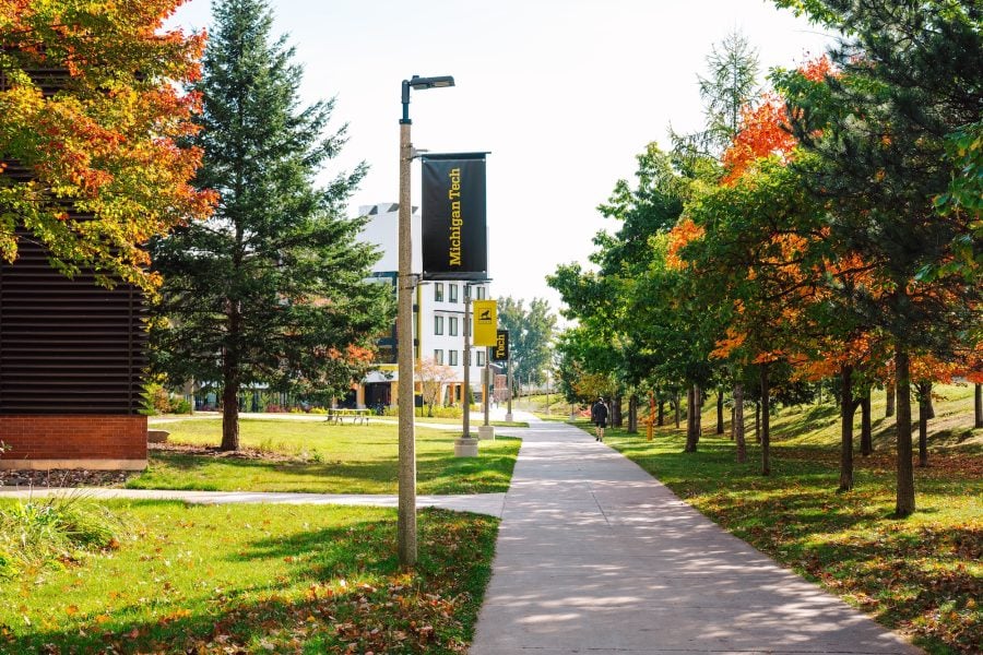 A scenic view of Michigan Technological University in the distance, surrounded by vibrant autumn foliage.
