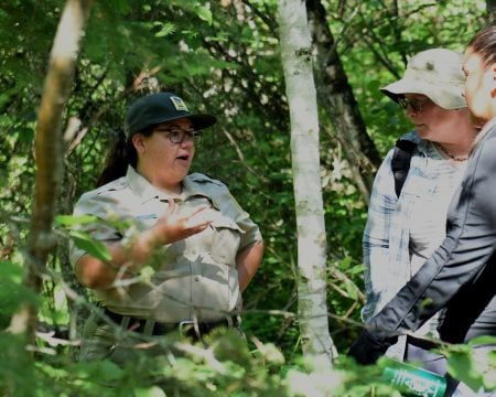Larissa talking to two indigenous students in the forest