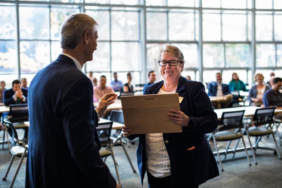 Kathy Halvorson receives plaque from Michigan Tech President Koubek in front of a roomful of seated people