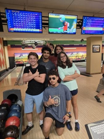 A diverse group of students posing for a photo in the bowling alley.