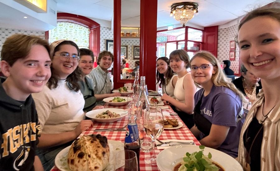 Eight smiling students eating dinner together