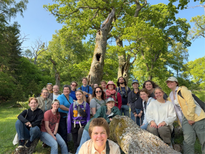 a class photo of teachers and students posed smiling in front of oak trees
