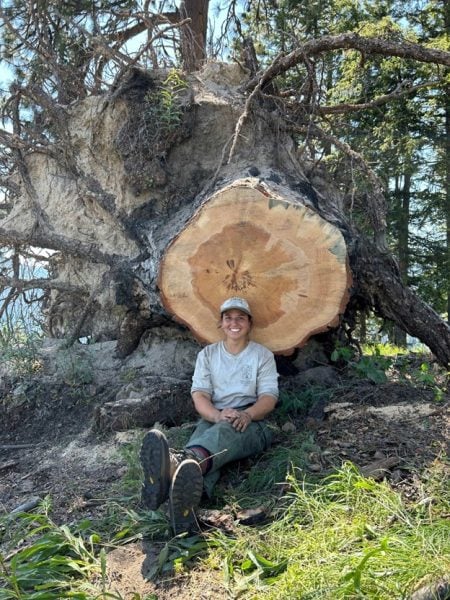 student sitting in front of fell tree