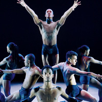 Dancer in the center of the stage with other dancers surrounding