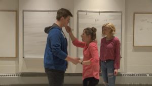 Two students hold hands while one other stands behind during a practice of A Midsummer Night's Dream