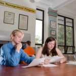 Two students sitting at a conference table studying.
